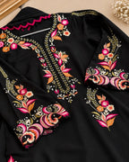 A black long-sleeve tunic or kurta with elaborate floral and paisley embroidery in pink, orange, gold, and white, shown in a styled flat-lay view.