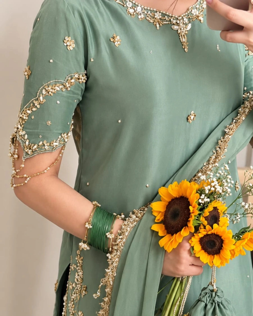 Sophisticated sage green wedding guest outfit featuring a flared sharara, embellished shirt hem, delicate golden detailing, and a statement chiffon dupatta.