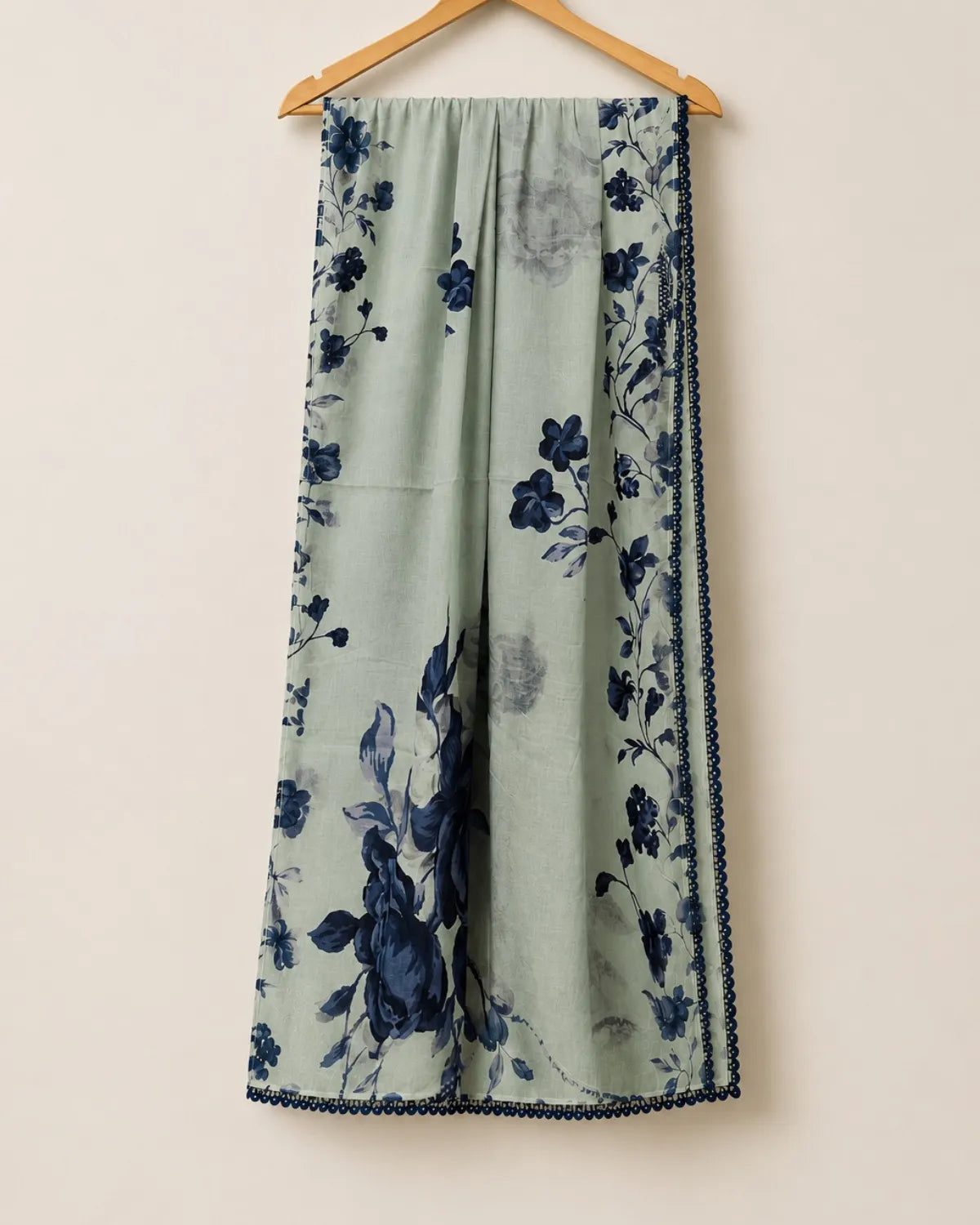Floral-patterned pants on a hanger against a beige background