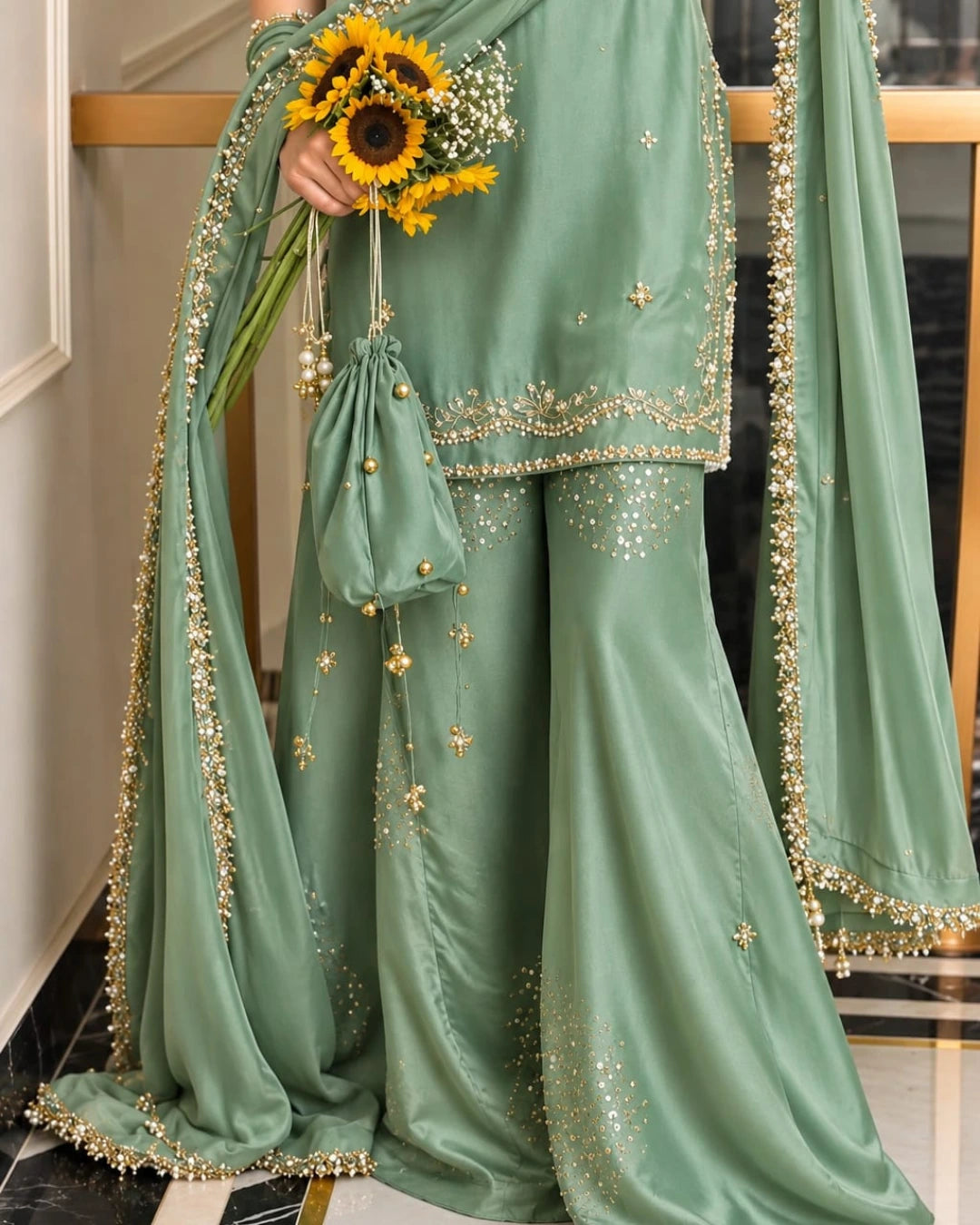 Beautiful sage green festive ensemble with delicate gold embellishments, an embroidered shirt, a flowing flared sharara, and an elegant chiffon dupatta.