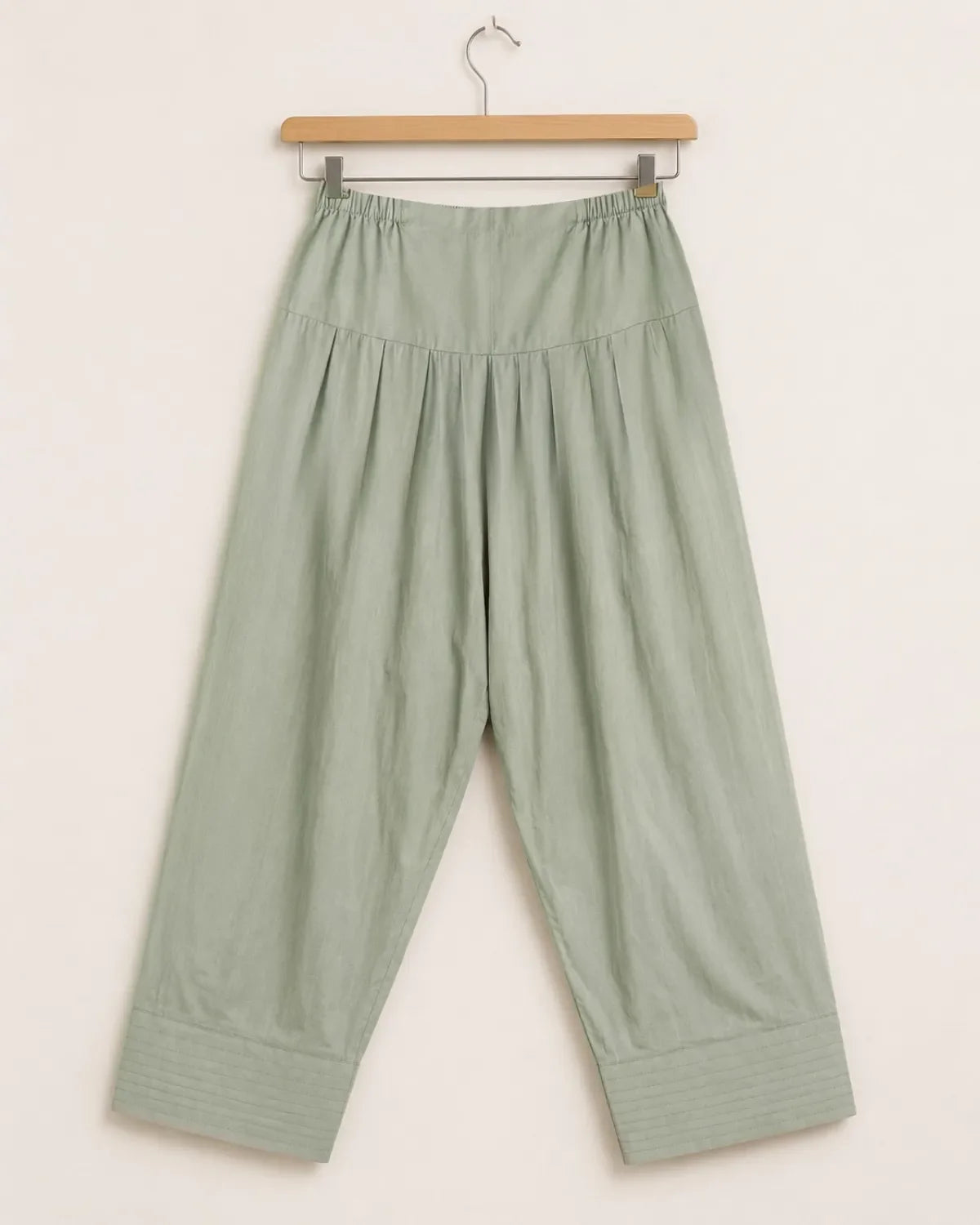 Green pants on a hanger against a white background