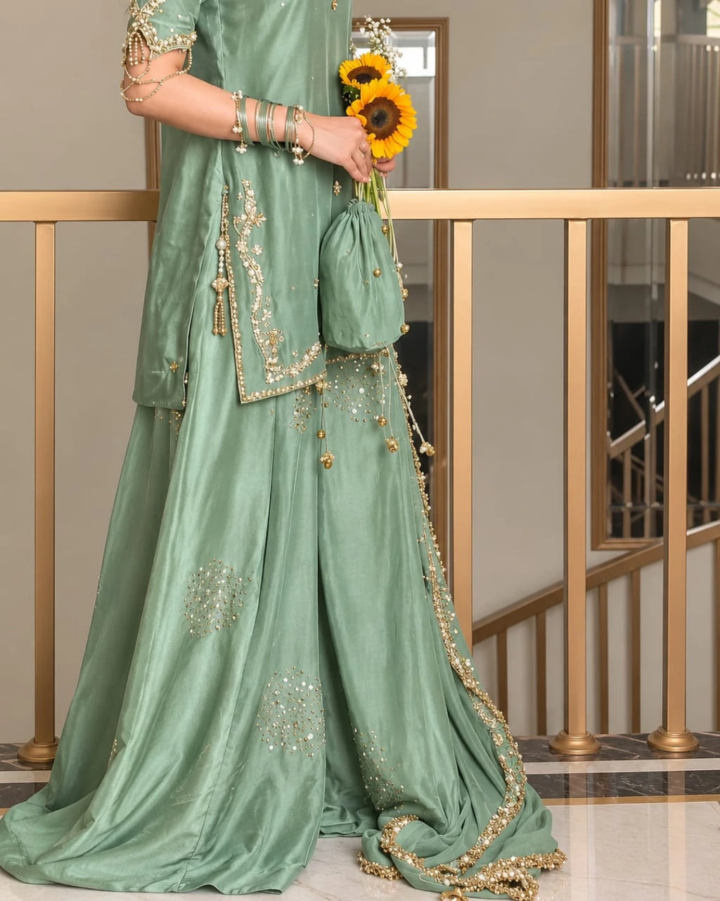 Sophisticated sage green wedding guest outfit featuring a flared sharara, embellished shirt hem, delicate golden detailing, and a statement chiffon dupatta.