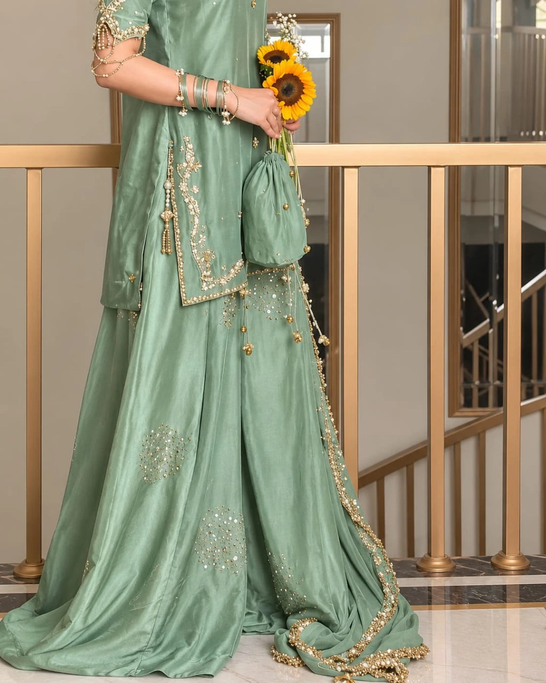 Sophisticated sage green wedding guest outfit featuring a flared sharara, embellished shirt hem, delicate golden detailing, and a statement chiffon dupatta.